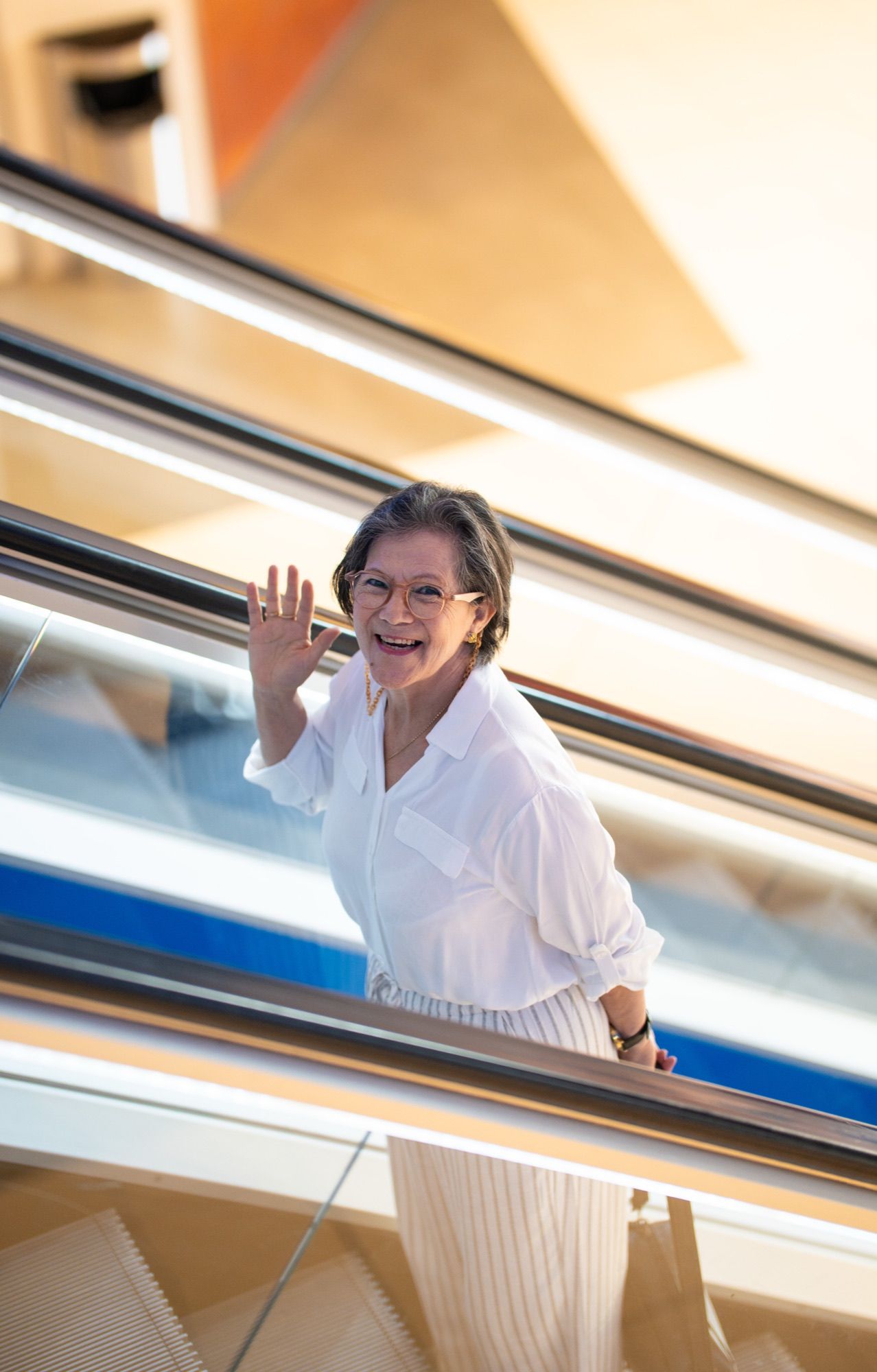 Mujer saludando desde la escalera mecánica