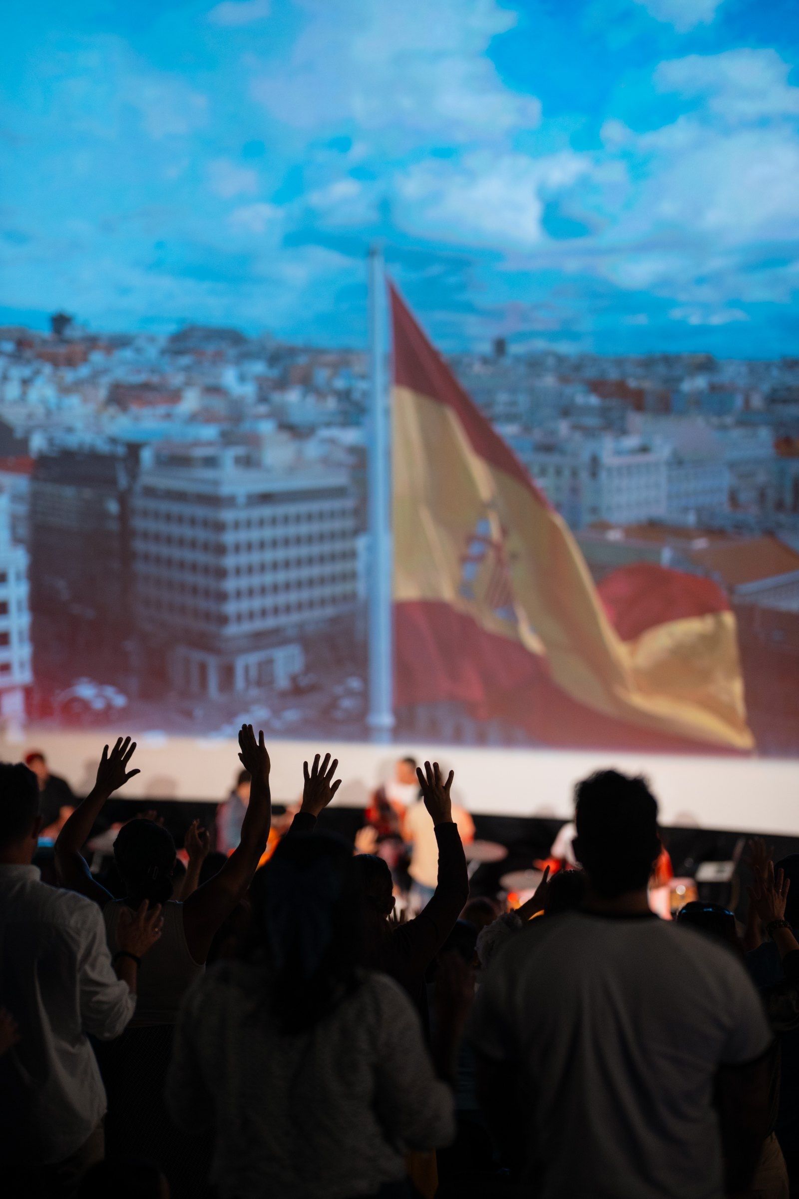 Manos levantadas y bandera de España durante una reunión de WAO Gijón